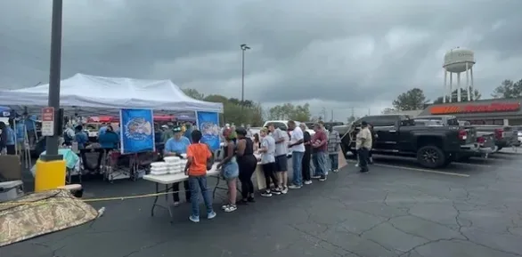 Neighbors lined up for disaster relief supplies under a Krewe of Neptune relief tent